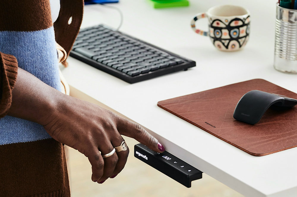 woman pressing remote control button on height adjustable office desk